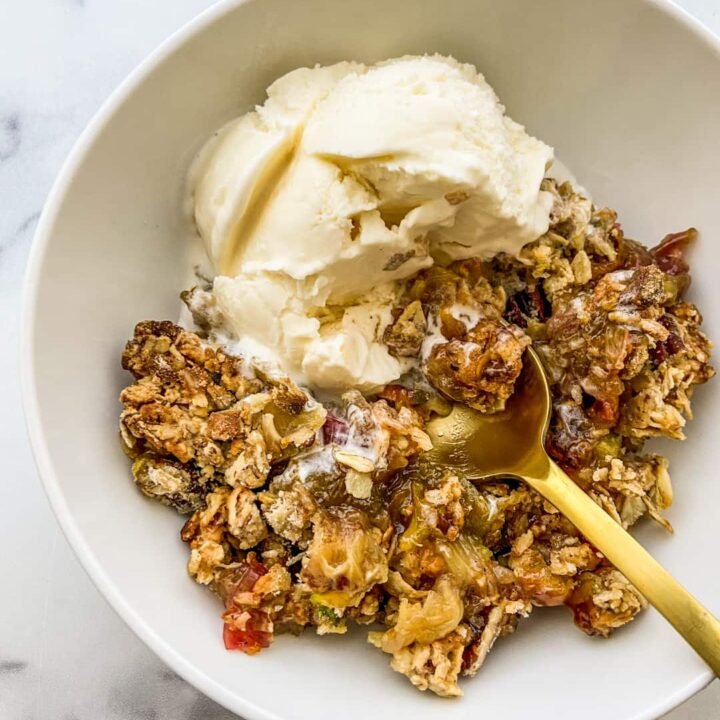 A bowl of rhubarb crisp with a scoop of vanilla ice cream.