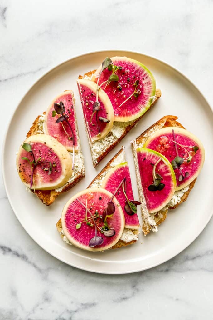 Watermelon radish toasts on a white plate.