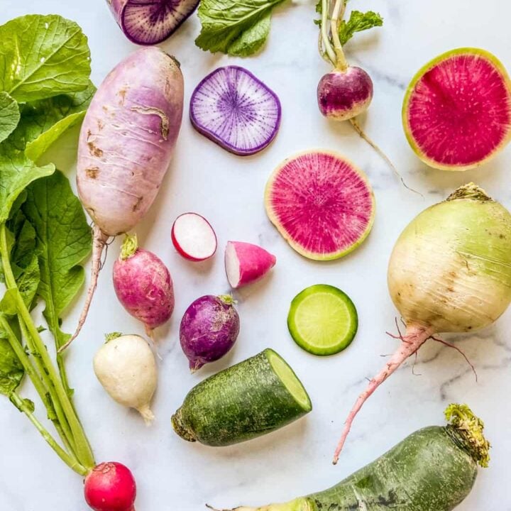 Different types of radishes on a marble background.