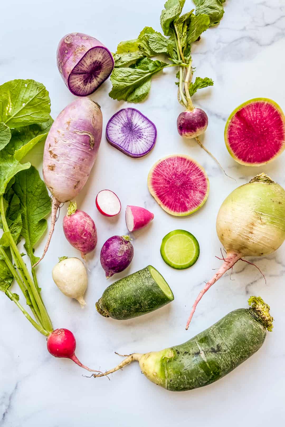 Different types of radishes on a marble background.