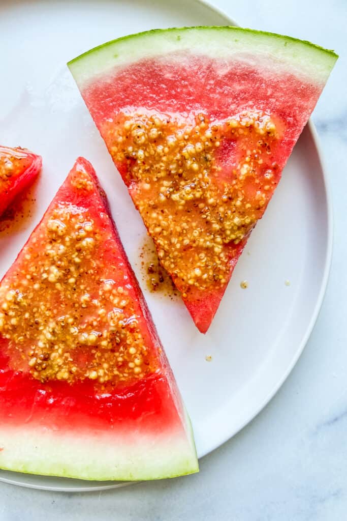 Two slices of watermelon with mustard sauce.