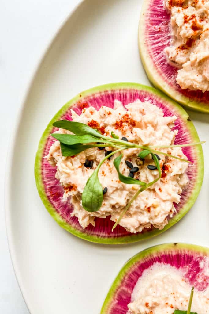 A closeup shot of a watermelon radish slice topped with tuna.