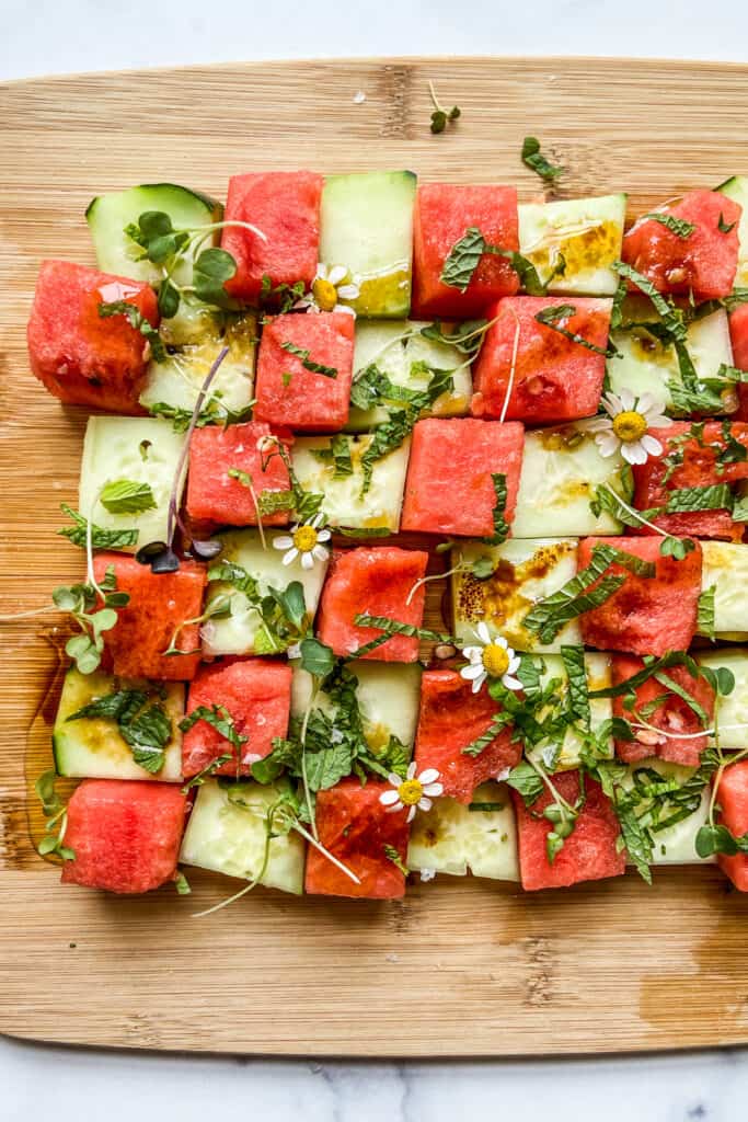 A cucumber watermelon mosaic salad on a cutting board.