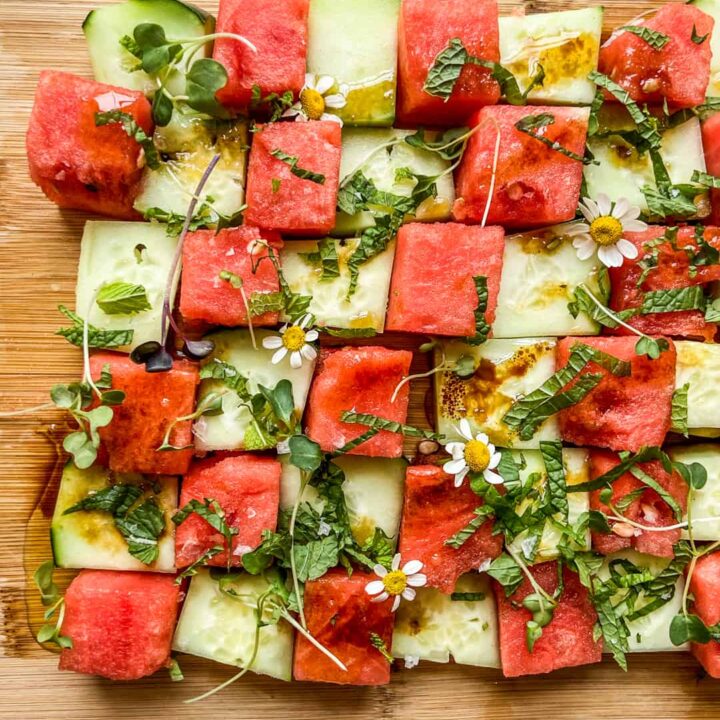 A cucumber watermelon mosaic salad on a cutting board.