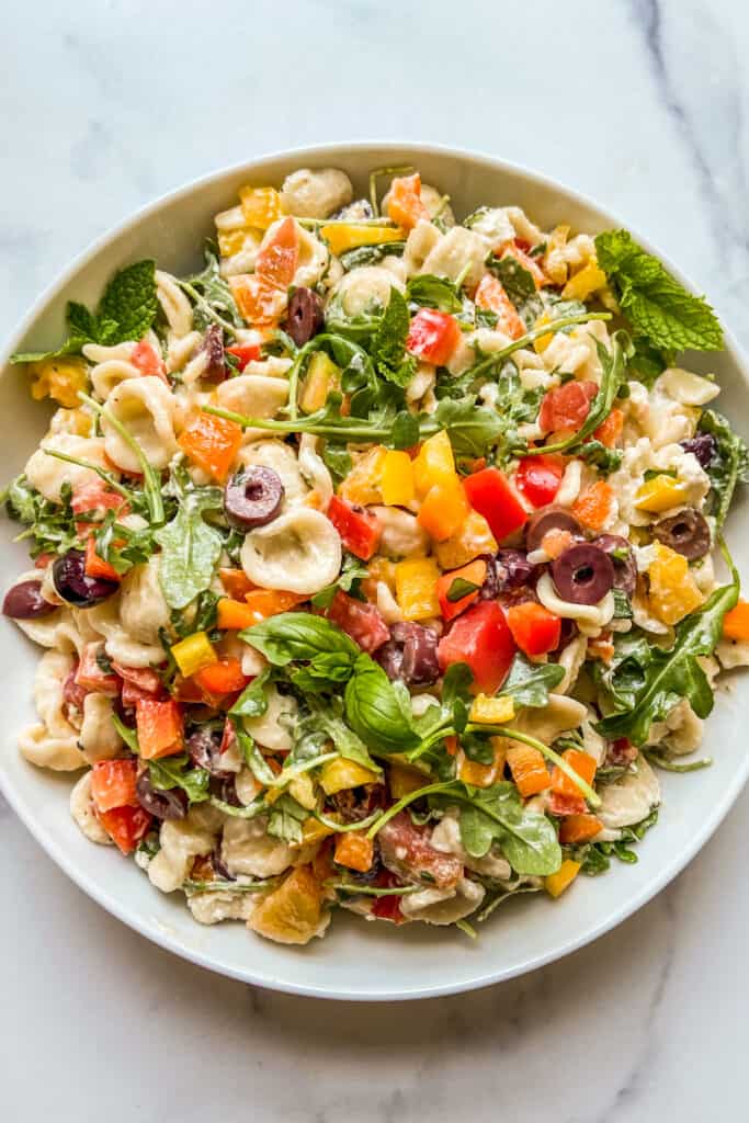 A Mediterranean pasta salad in a large white serving bowl.