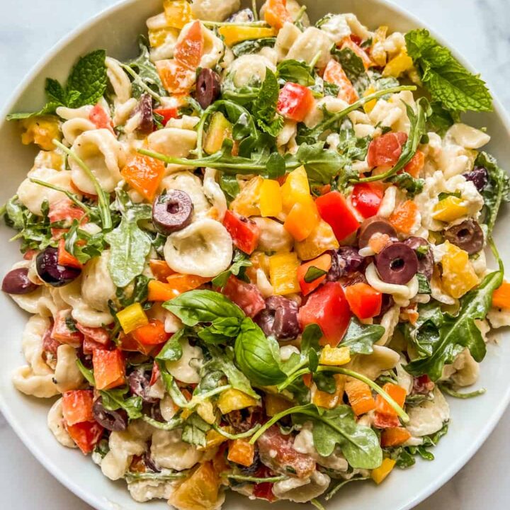 A Mediterranean pasta salad in a large white serving bowl.