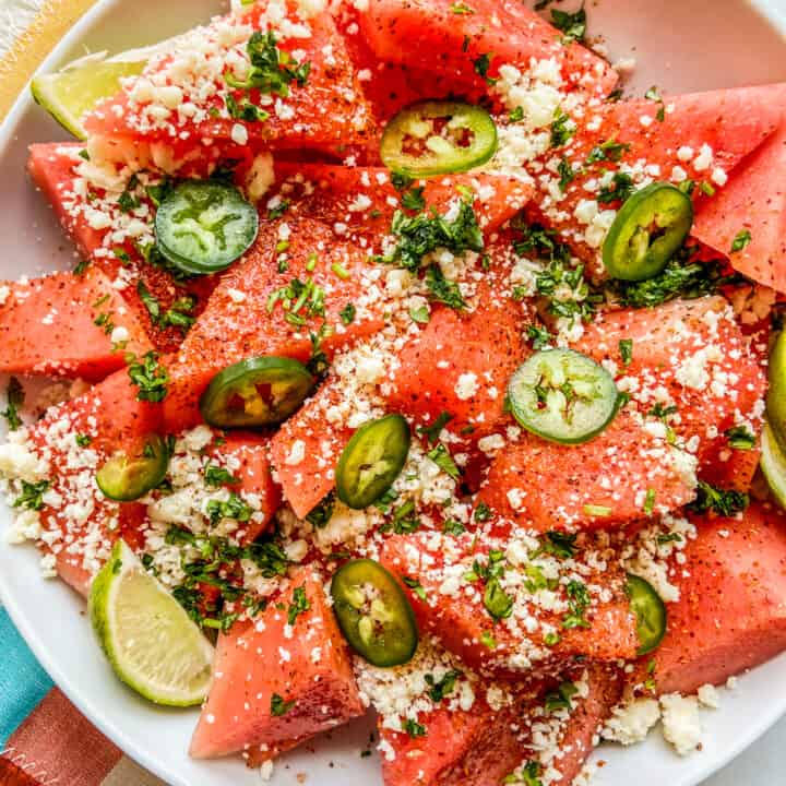Mexican watermelon salad in a large white bowl on a colorful napkin.