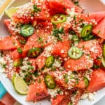 Mexican watermelon salad in a white bowl on top of a colorful napkin.