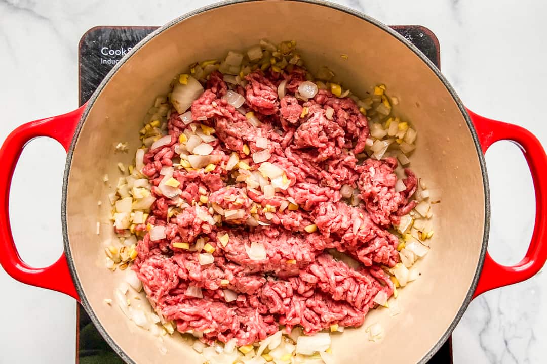 Adding ground beef to sauteed onions.