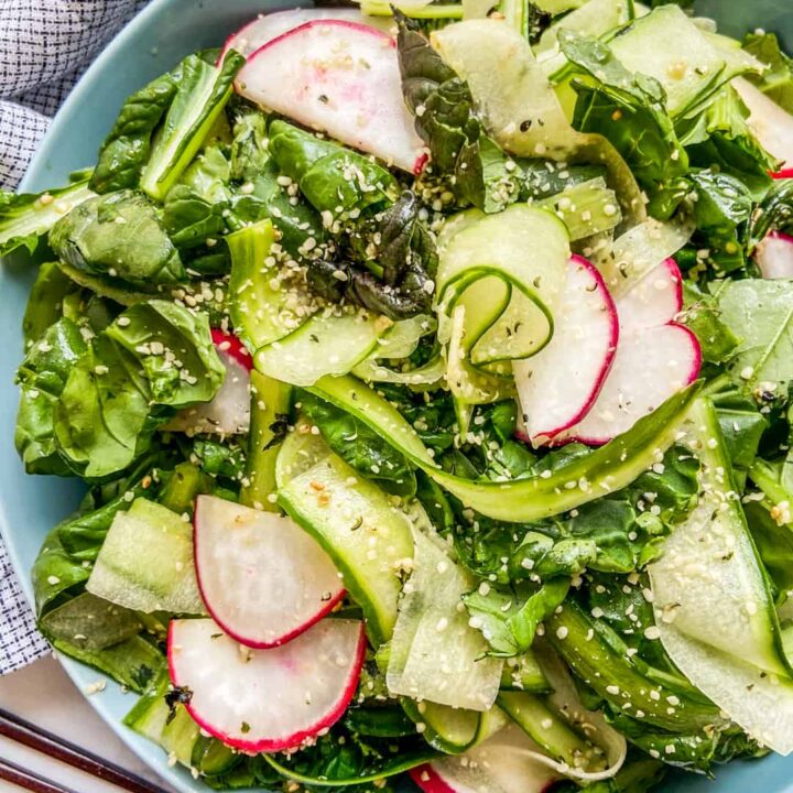 Tatsoi greens salad in a blue serving bowl next to a napkin and chopsticks.