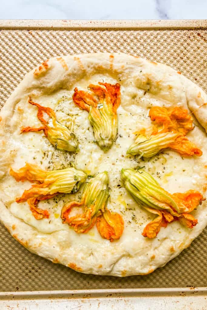 Zucchini flowers added to the pizza before it goes in the oven.