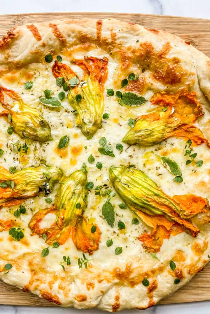 A closeup shot of a zucchini blossom pizza.