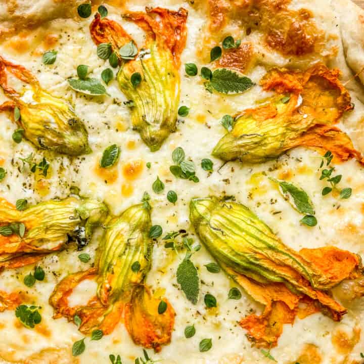 A closeup shot of a zucchini blossom pizza.