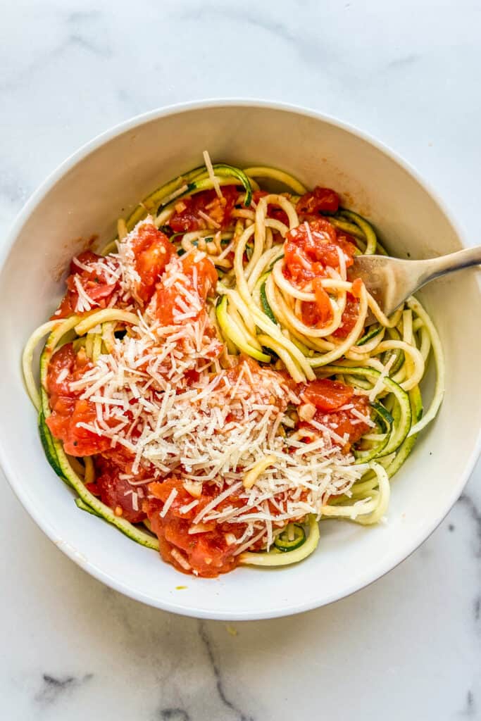 Zoodles with marinara sauce in a white bowl with a fork.