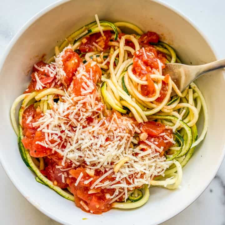 Zoodles with marinara sauce in a white bowl with a fork.