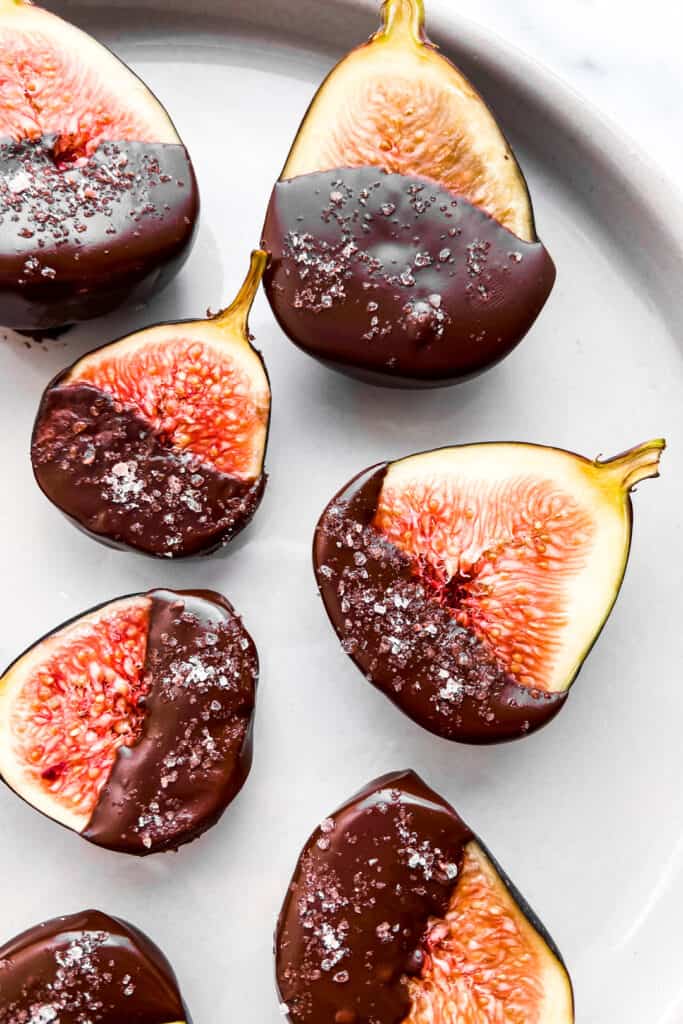 A closeup of dark chocolate dipped figs on a plate.