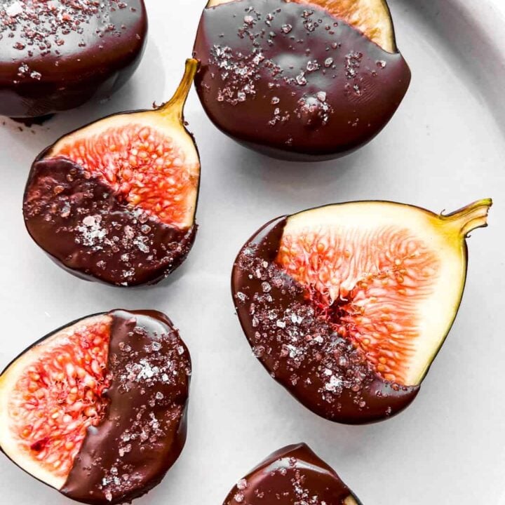 A closeup of dark chocolate dipped figs on a plate.