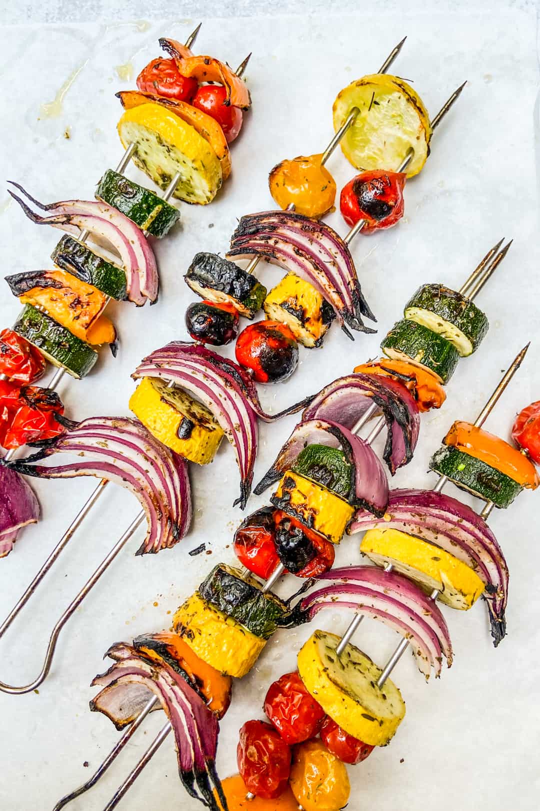 Grilled vegetables on metal skewers after coming off the grill.