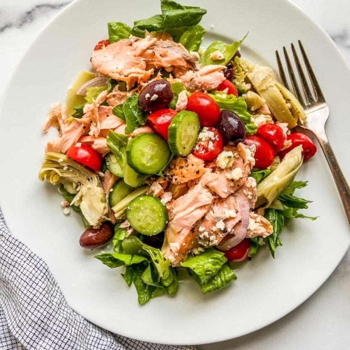 A large white plate with a Mediterranean salmon salad.