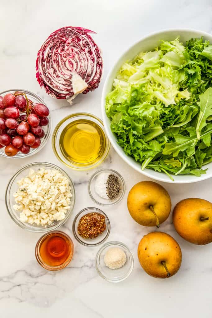 A bowl of lettuce, Asian pears, blue cheese, a half a radicchio, olive oil, grapes, salt and pepper, sugar, mustard, and red wine vinegar. 