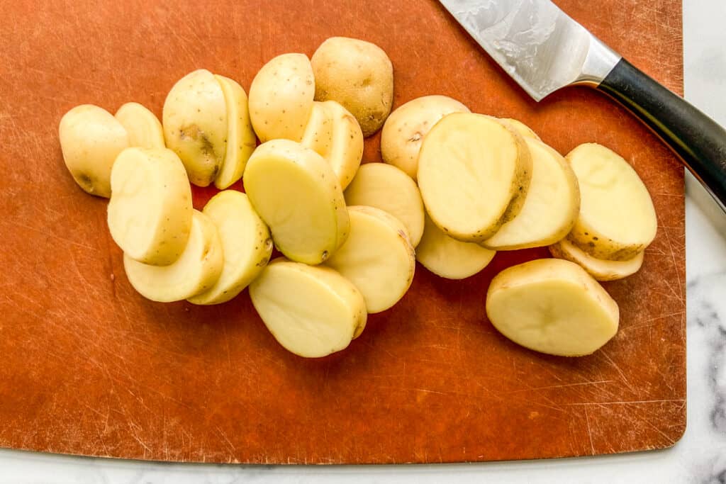 Chopped yellow potatoes on a brown cutting board.