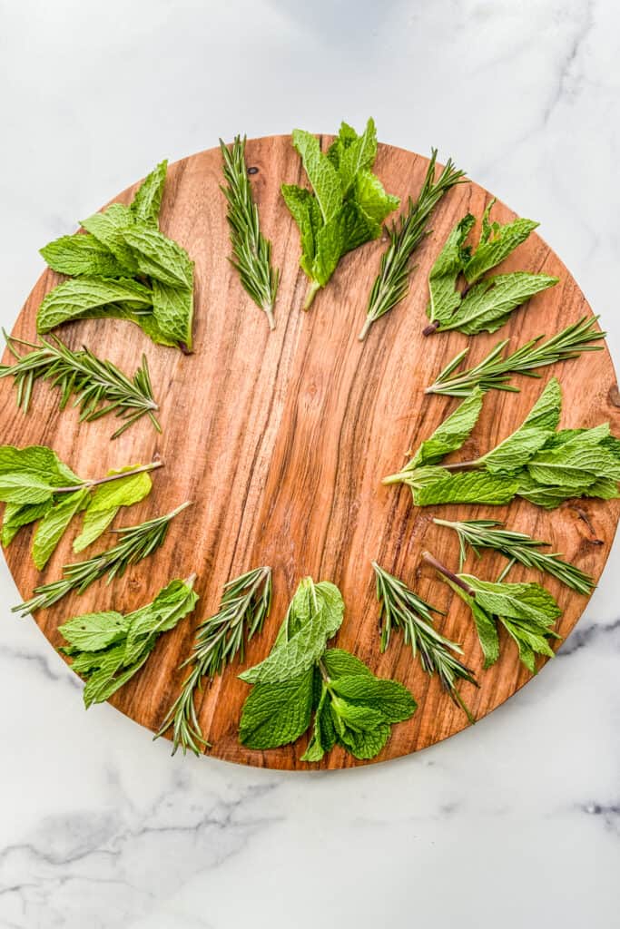 Fresh herbs on a large wooden plate.