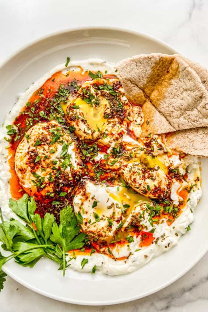 A bowl of poached eggs, yogurt, and chili butter sauce.