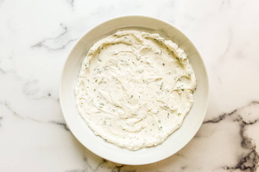 Herbed yogurt spread onto a large, low bowl.