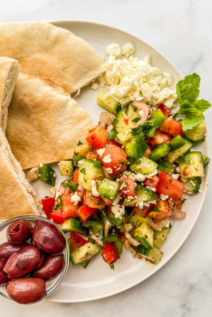 Turkish shepherds salad on a plate with kalamata olives and pita bread.