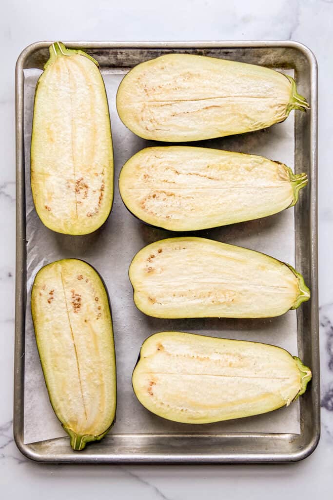 Halved eggplants topped with salt on a baking sheet.