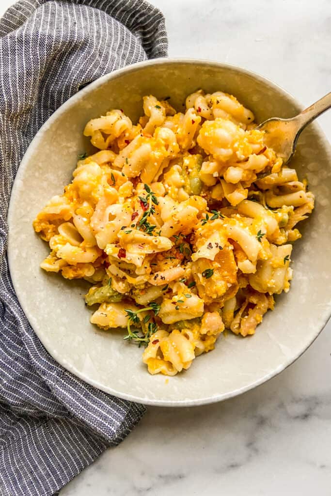 A bowl of butternut squash feta pasta next to a blue and white napkin.