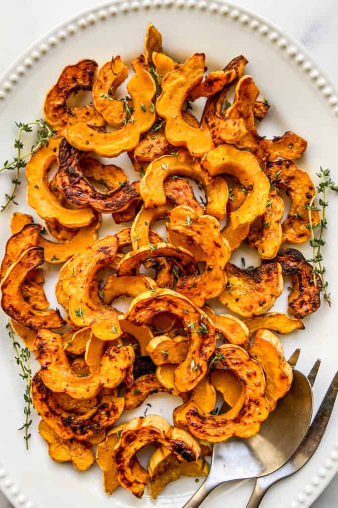 Roasted delicata squash on a large white serving dish.