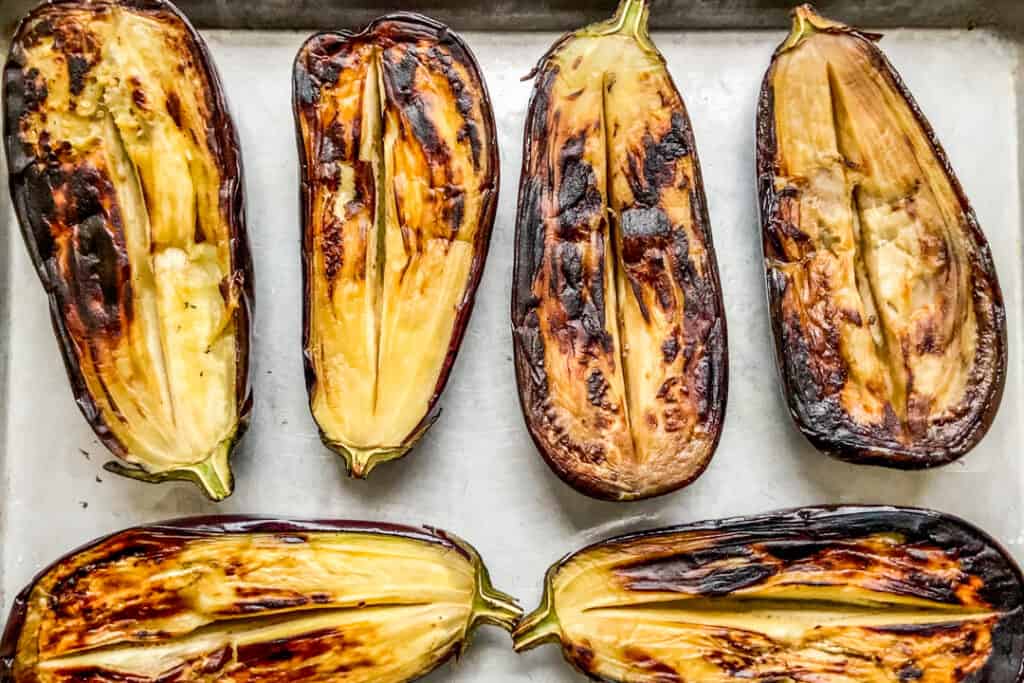 Fried eggplant halves on a baking sheet.