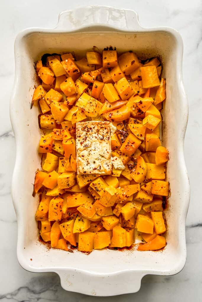 Baked butternut squash with feta in a large white baking dish.