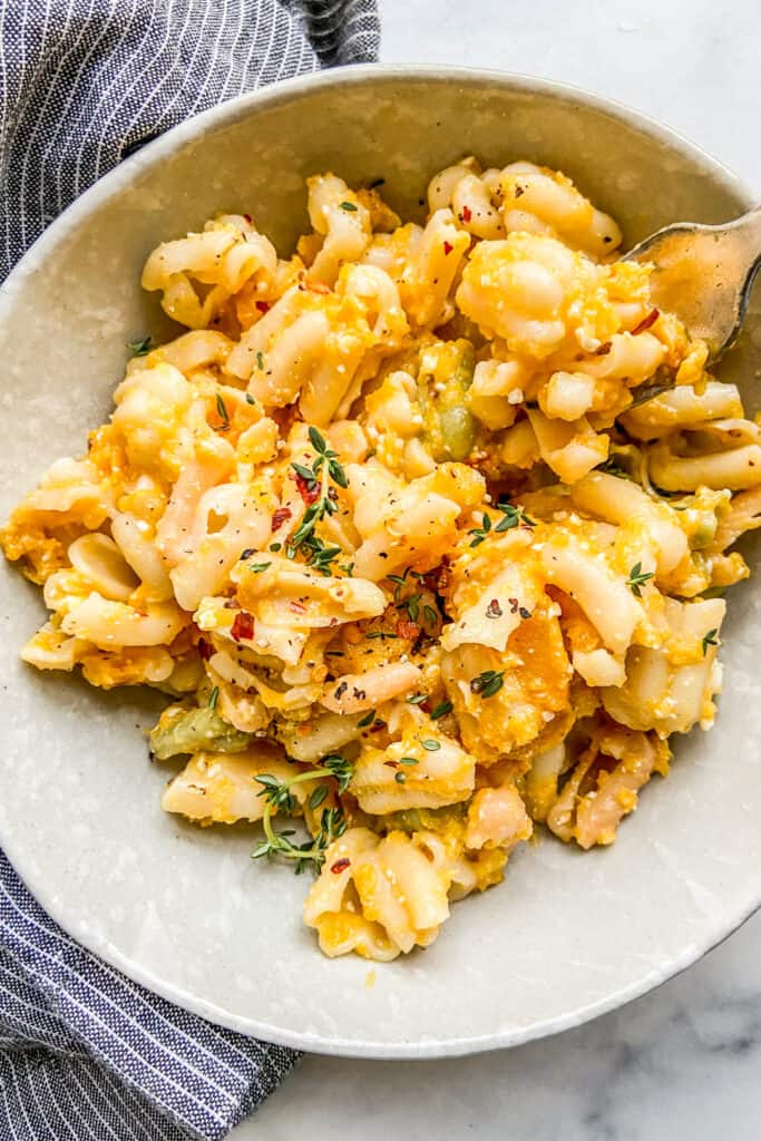 A bowl of butternut squash feta pasta next to a blue and white napkin.