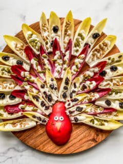 An overhead shot of a Thanksgiving appetizer tray made from endives, feta dip, and a pear.