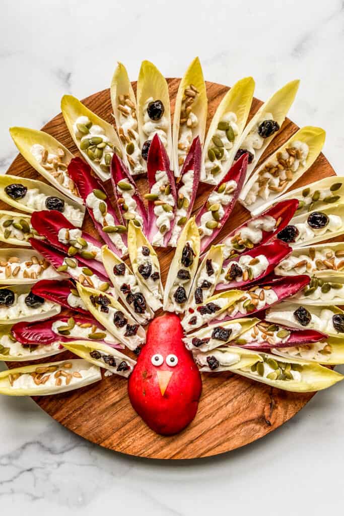 An overhead shot of a Thanksgiving appetizer tray made from endives, feta dip, and a pear.