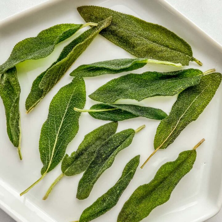 A white plate with crispy sage leaves.