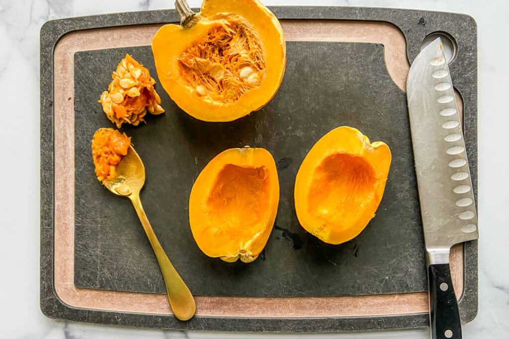 Cutting carnival squash on a cutting board.