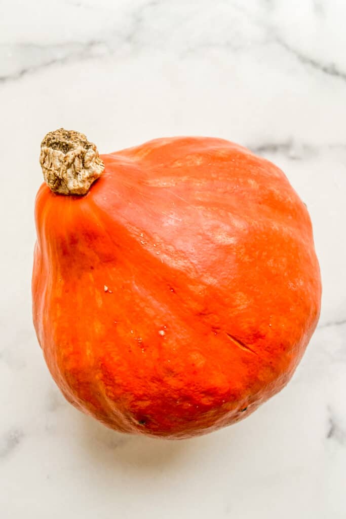 Red kuri squash on a marble background.