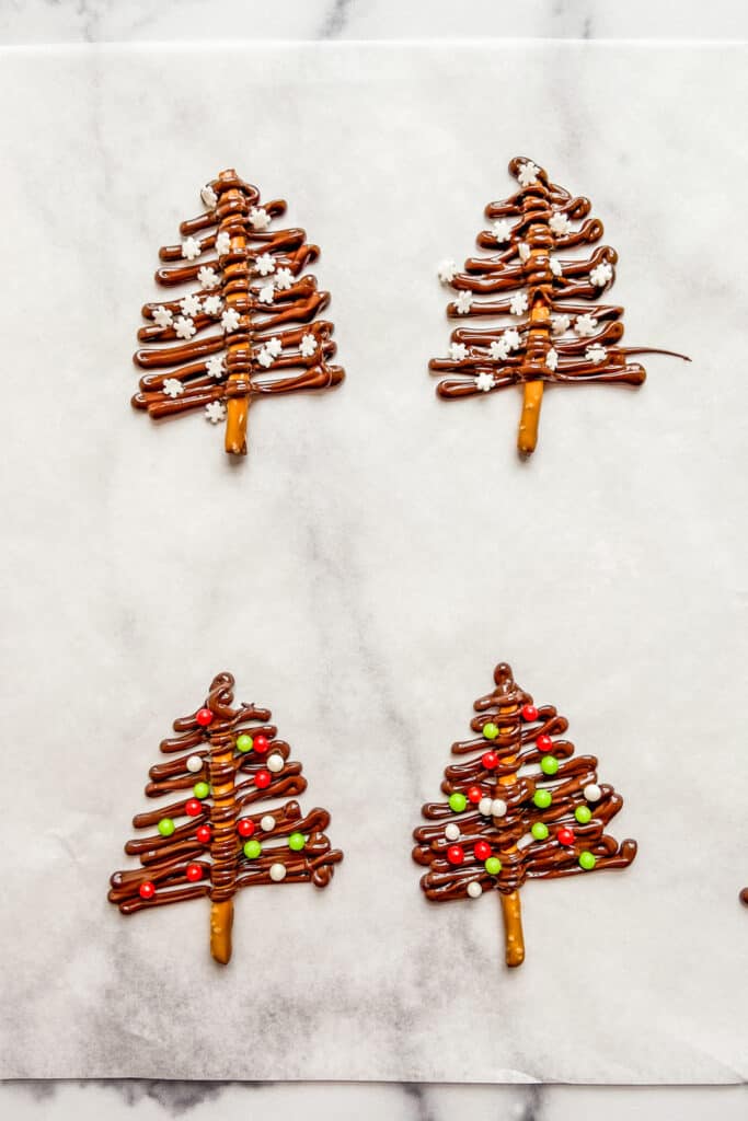Dark chocolate Christmas trees drying on a sheet of parchment paper.