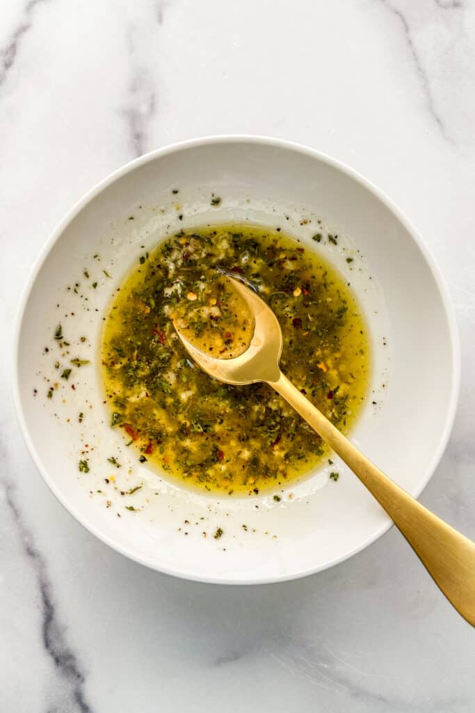 Olive oil and spices in a bowl with a gold spoon.