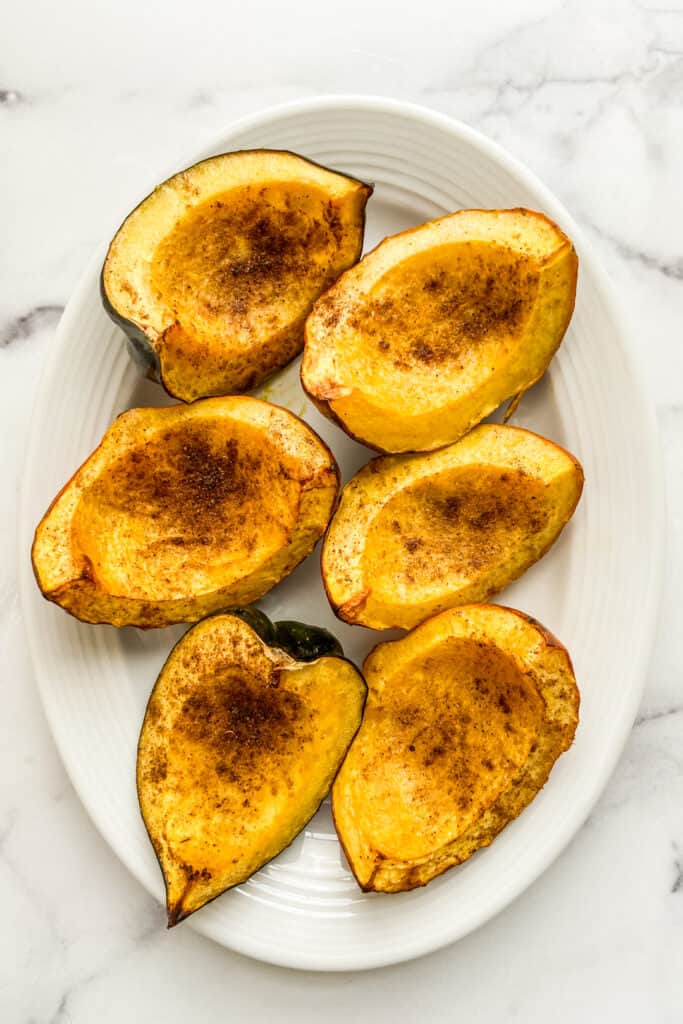 Roasted acorn squash on a white serving dish.