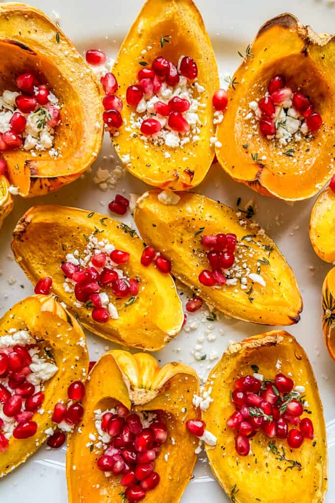 A closeup shot of roasted carnival squash topped with feta and pomegranate.