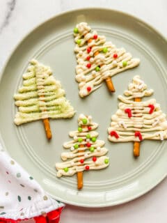 Four white chocolate Christmas trees on a light green plate.