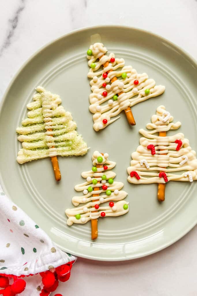 Four white chocolate Christmas trees on a light green plate.