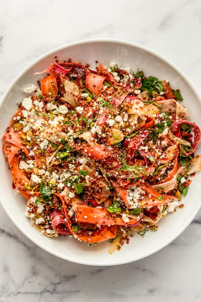 A rainbow carrot quinoa salad in a large white salad bowl.