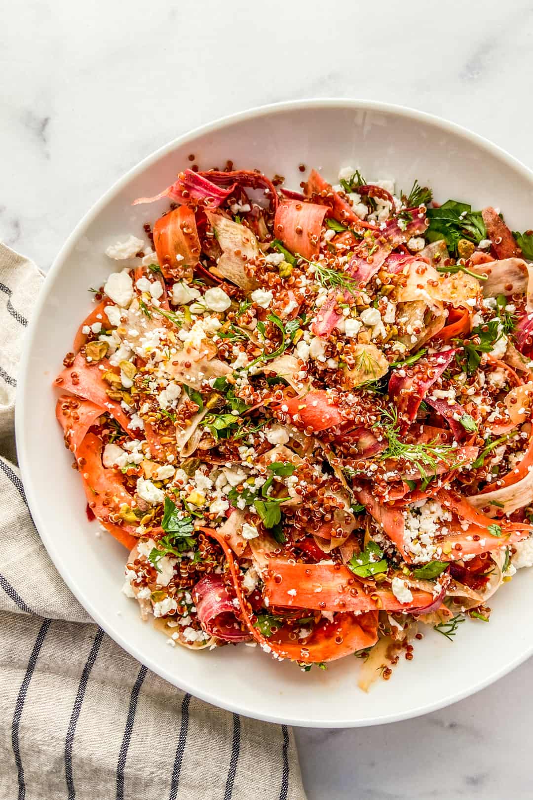 Rainbow carrot quinoa salad in a white serving bowl.