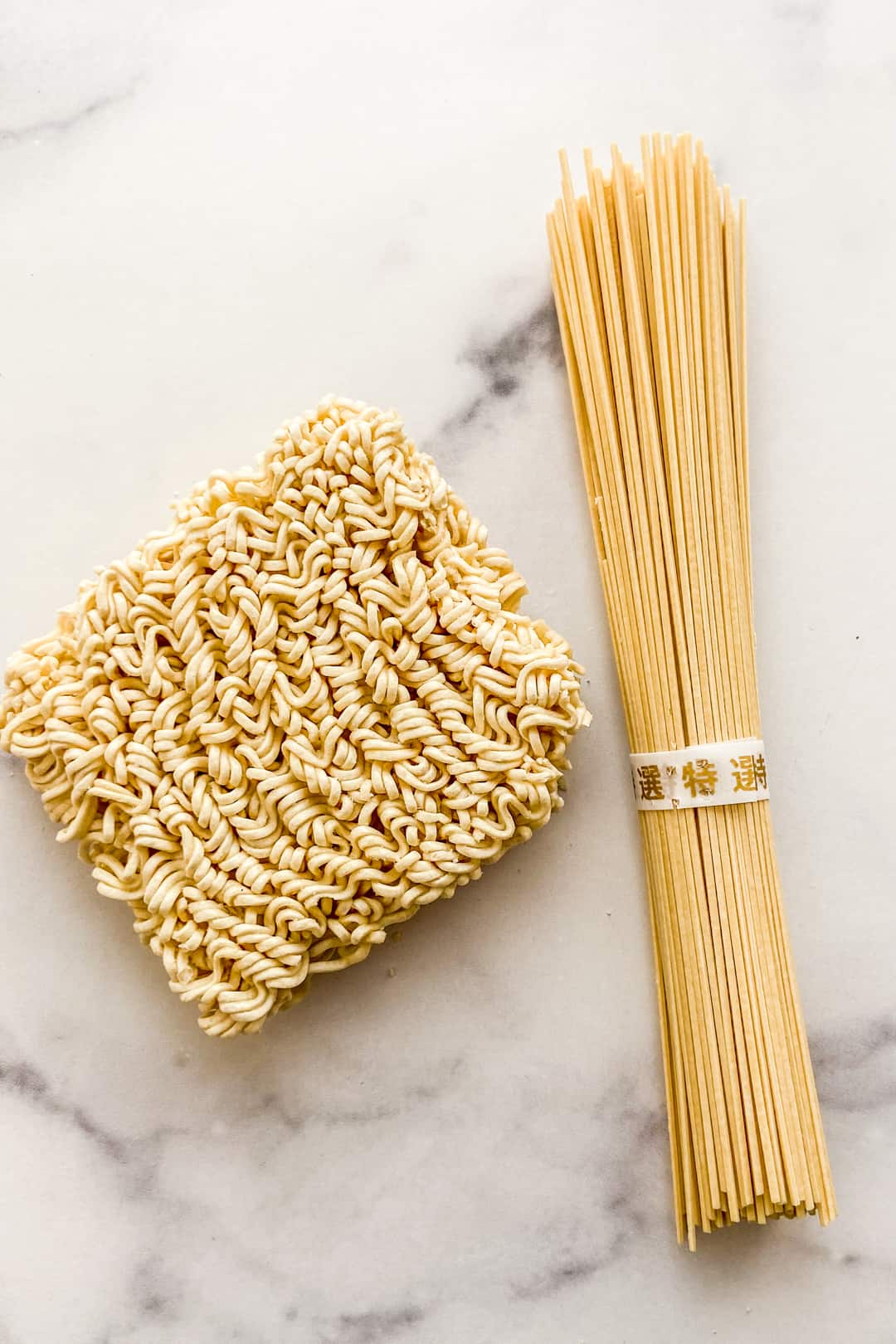 Two types of ramen noodles on a marble background.