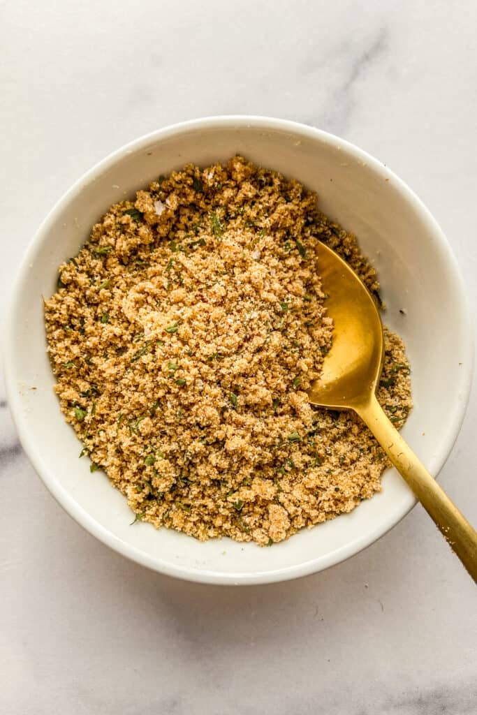 A ramen seasoning spice blend in a small white bowl with a gold spoon.